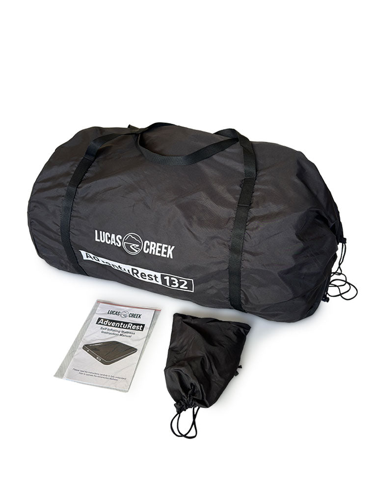 Black Lucas Creek AdventuRest 132 self-inflating mattress packed in a large carry bag, shown with its instruction manual and a smaller black drawstring bag.